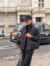 A lady wears a black down garment in cold weather.